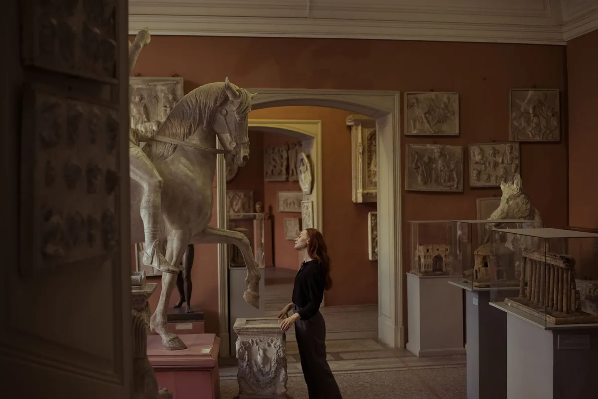 Besucher in beleuchteten Museumsgalerien bei Nacht, Silhouetten vor Kunstinstallationen