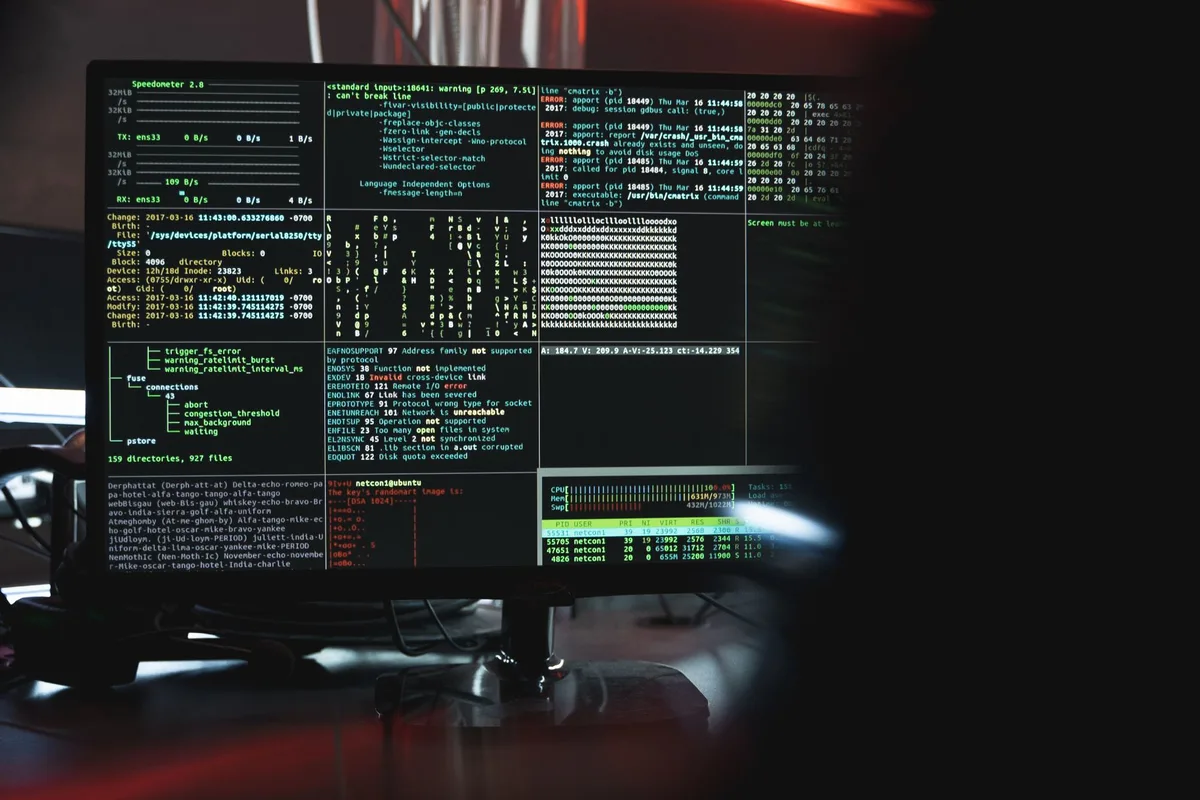 Hände an einer Tastatur mit Sicherheitssymbolen auf einem dunklen Bildschirm im Hintergrund