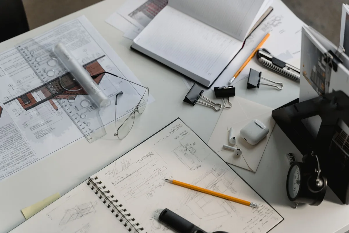 Architekt an einem Schreibtisch mit Bauplänen, Modellen und Zeichnungen in einem modernen Atelier