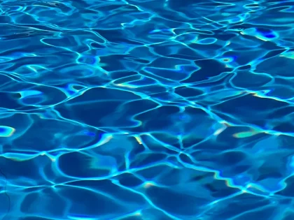 Kind beim Schwimmunterricht in einem Hallenbad mit Unterstützung eines Trainers