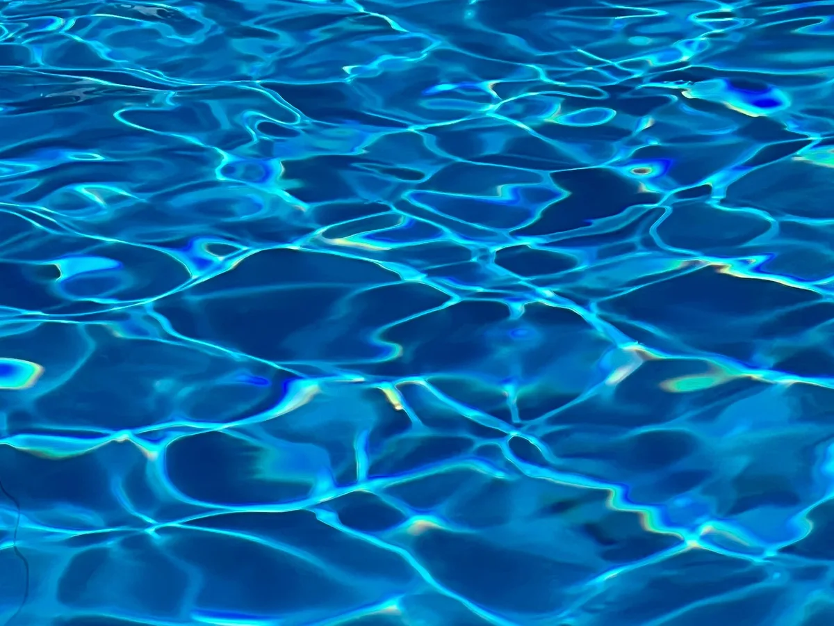 Kind beim Schwimmunterricht in einem Hallenbad mit Unterstützung eines Trainers