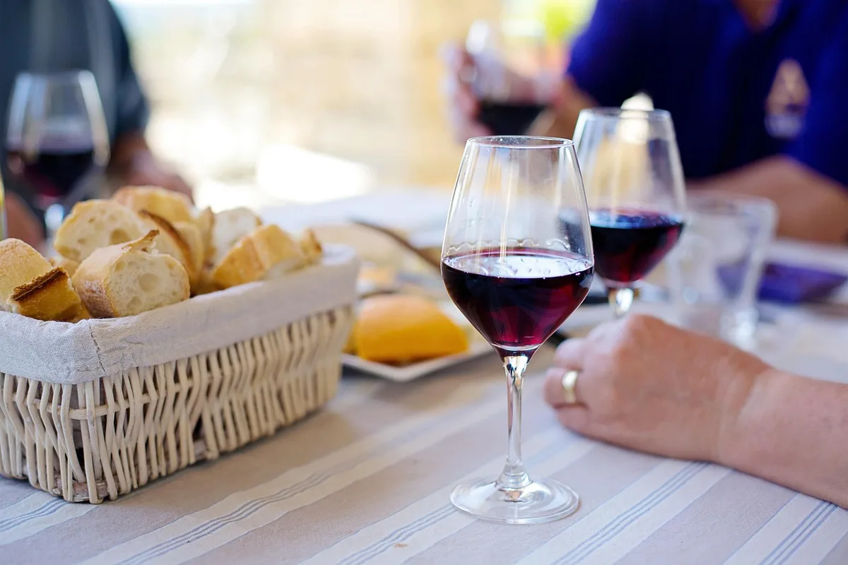 Picknick mit Wein und Käse auf Bierbänken in sommerlicher Umgebung