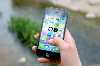 Hand hält leuchtend ein Smartphone, umgeben von verschwommenen digitalen Geräten in Dämmerung