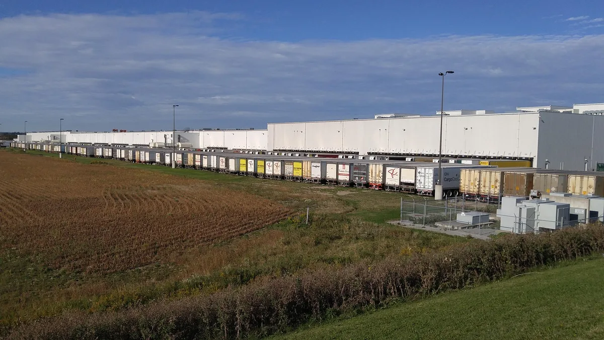 Lieferwagen und Logistik-Arbeiter beim Entladen von Waren in einem Lager