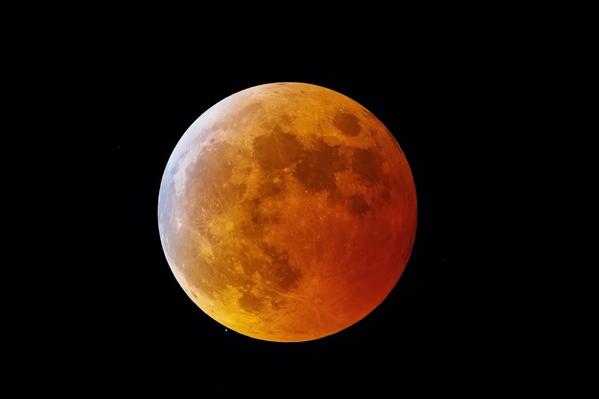 Mondfinsternis am frühen Morgenhimmel über dunkler Landschaft