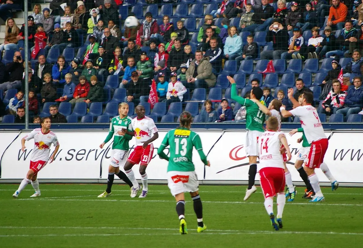 Anonyme Fangruppen mit Schals und ein Trainingsball vor einem Clipboard in einer Stadionumgebung