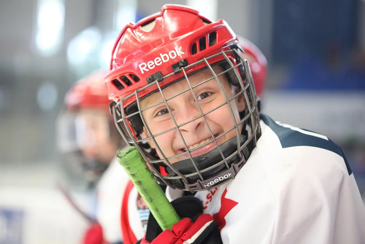 Silhouette von Hockeyschlägern und Puck auf dem Eis vor unscharfen Spielern
