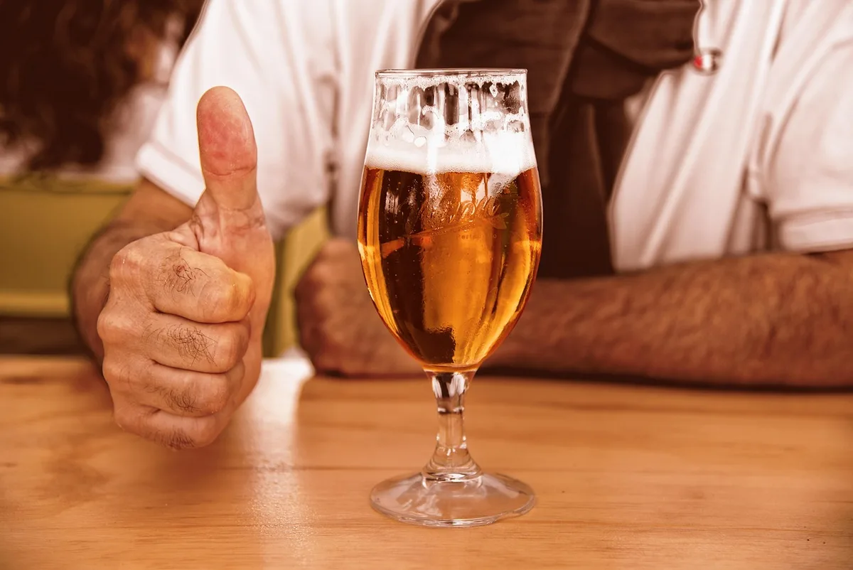 Teller mit Currywurst neben einem Glas Bier auf einem Kneipentisch
