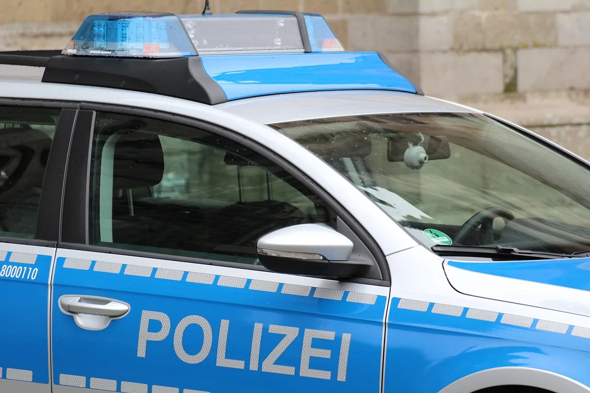 Nachbar spricht mit älterem Mann vor Haus, Polizei im Hintergrund