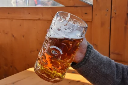 Biergarten am Abend mit Besuchern an Holztischen und Live-Musikern im Hintergrund