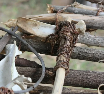 Innenansicht eines trockenen Brunnenbodens mit verstreuten Knochen und Keramik, Hand mit Kelle im Vordergrund