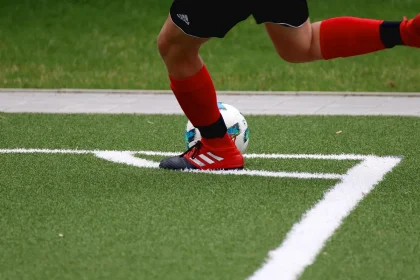 Fußballschuh und Sportuhr auf Kunstrasen nahe Seitenlinie, Symbol für schnelle Außenspieler