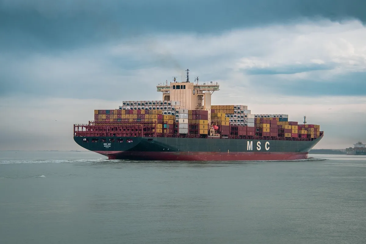 Fabrikhalle mit Förderbändern und Lkw vor Versandbereich als Symbol für Exportstärke