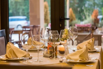 Terrasse eines Restaurants mit Tischen, warmem Licht und Feuerstelle am Abend