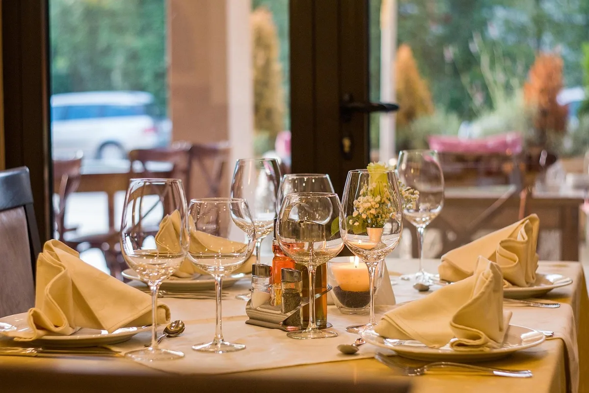 Terrasse eines Restaurants mit Tischen, warmem Licht und Feuerstelle am Abend